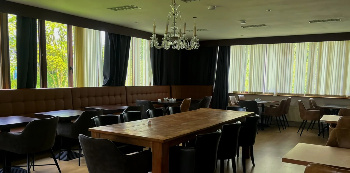 De zaal met kristallen luster, lange tafel en zicht op het groen