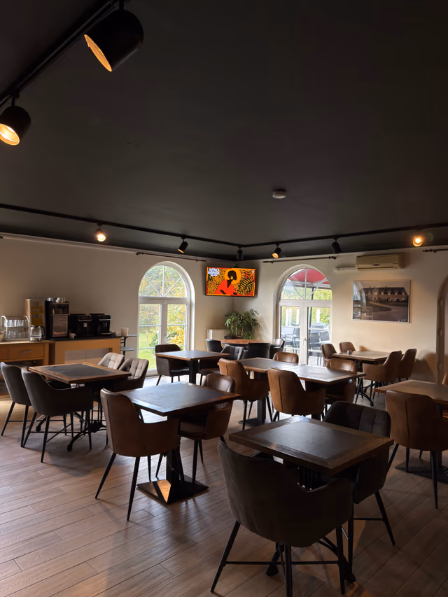 Function room with tables set for guests and a painting of the hotel